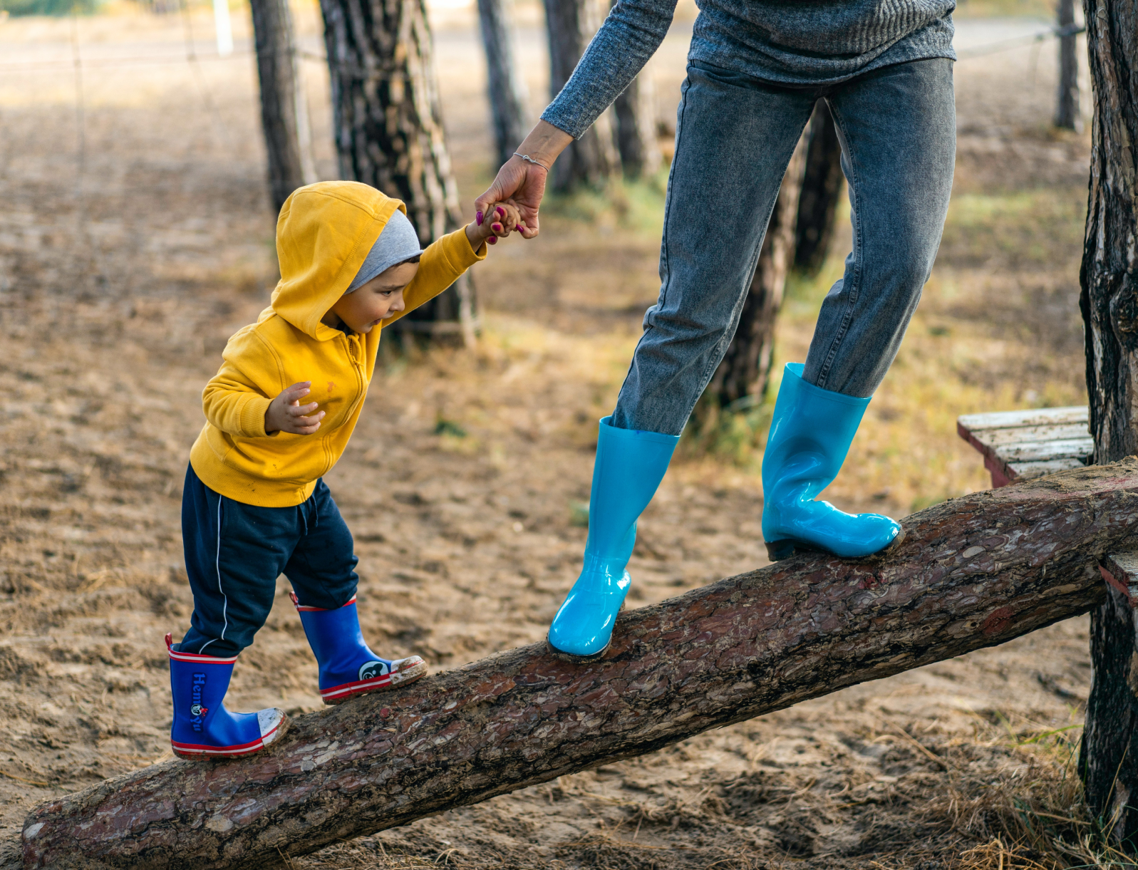 Een kind met ouder staan op een omgevallen boom
