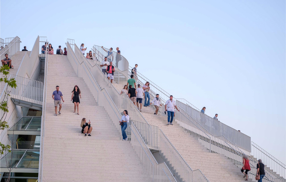 Een sfeerfoto van mensen op die lopen, spelen en zitten op een gebouw van MVRDV